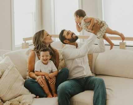 A family is sitting on a couch playing with their children.