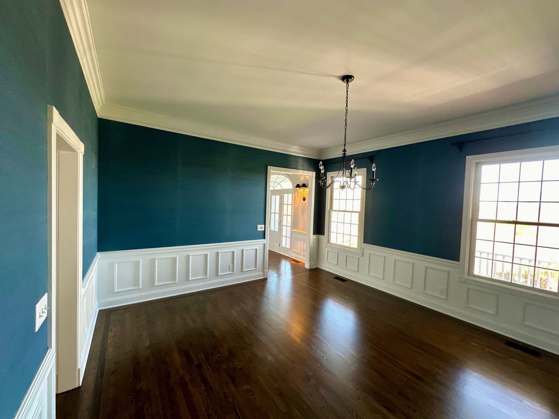 An empty dining room with dark wood floors and blue walls.