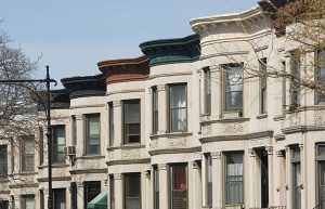 rent burdened - row of apartment buildings in nyc with different colored roofs