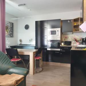 a kitchen with black cabinets and a table with chairs at FeWo Regenbogen. Jeden Tag bunt starten! in Altenau