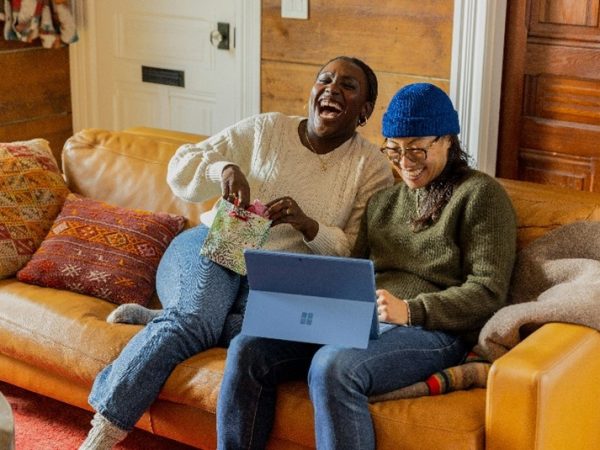 Two people sitting on a couch enjoying what they're watching on their Microsoft Surface device