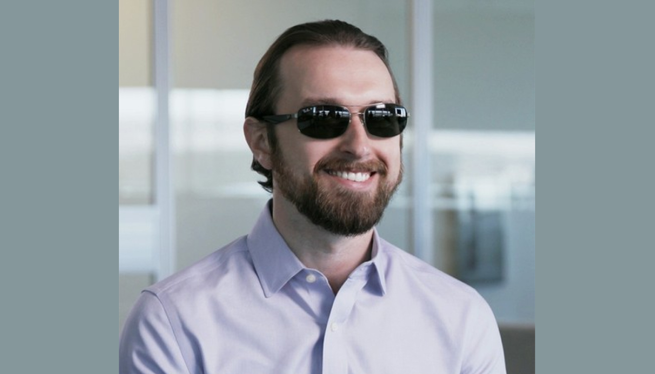 Petr Kucheryavy smiling to the camera. He's wearing a light colored shirt and sunglasses.