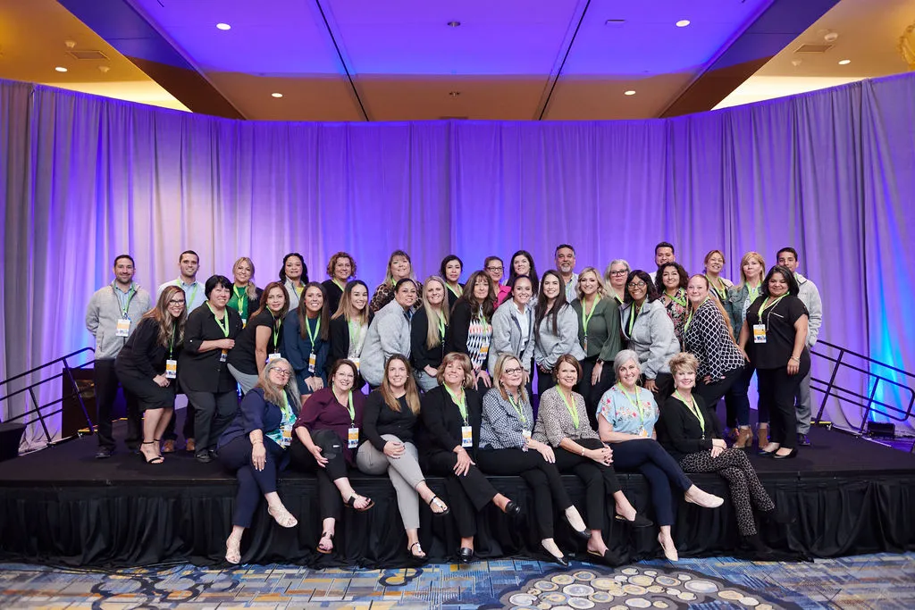 Large group of asset employees on stage at a conference