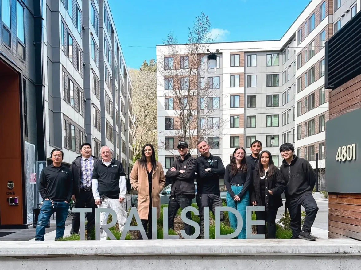 asset living team standing behind trailside property sign