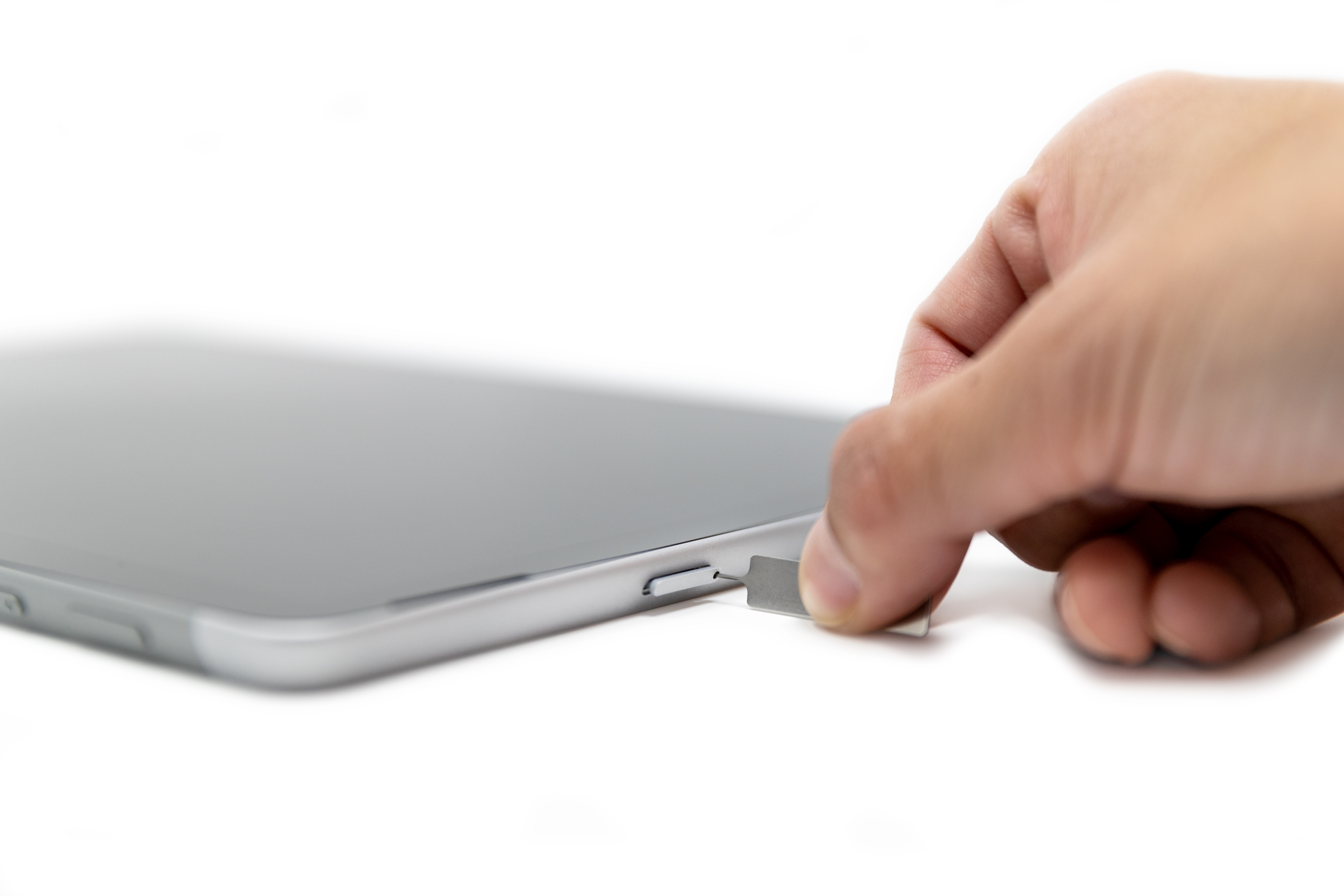 A person inserting a SIM pin into the SIM card slot of a Surface Go 2.