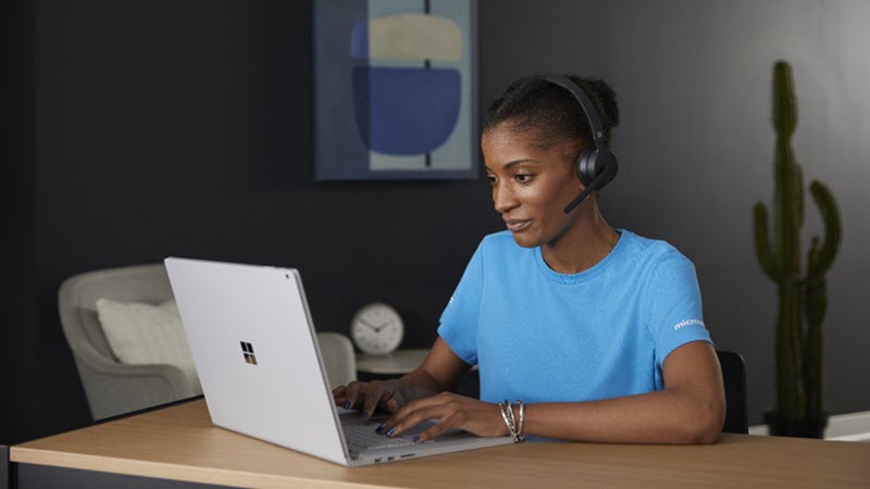 Mujer con auriculares mientras usa un portátil