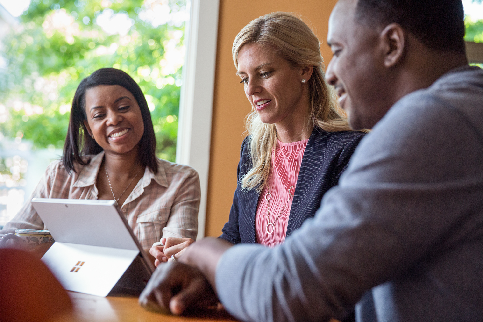 Photo de trois personnes regardant une Microsoft Surface ensemble