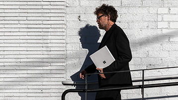 Un uomo che cammina con un Surface Book in mano