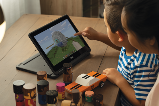 Een jonge jongen gebruikt Minecraft op een laptop terwijl een vrouw over zijn schouder kijkt