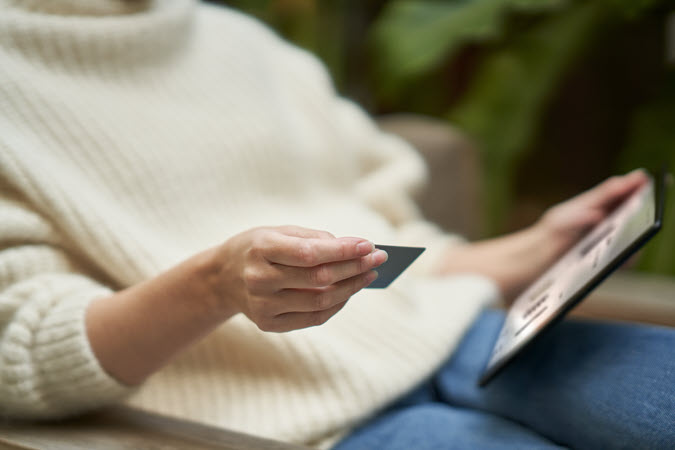 Mulher segurando um card de crédito e portátil