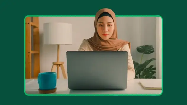 Woman wearing a hijab, looking at research insights on laptop