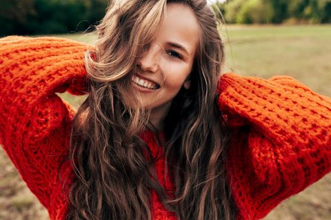 Eine junge Frau mit einem gestrickten orangefarbenen Pullover