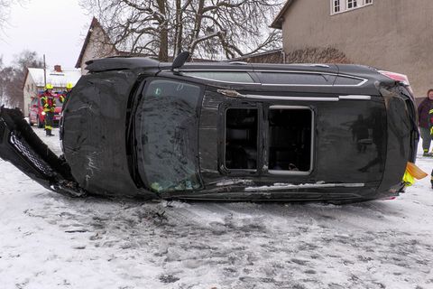 Nach einem Autounfall bei Winterwetter in Deutschland liegt ein grauer SUV auf der linken Seite