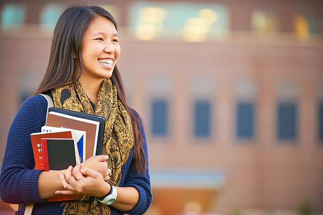 Eine junge Frau hält Bücher in der Hand.