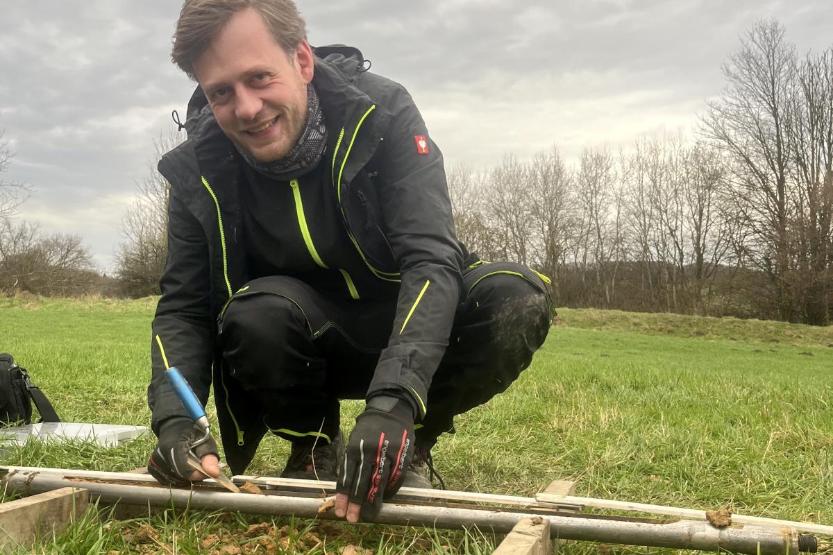 Fündig geworden: Der Archäologe Florian Jüngerich hat bei einer Rammkernsondierung ein Stück verkohltes Holz in der Bodenprobe entdeckt