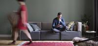 Man sitting on the couch in the living room while his girlfriend passing in the foreground