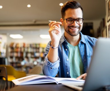 Smiling male student working and studying in a library