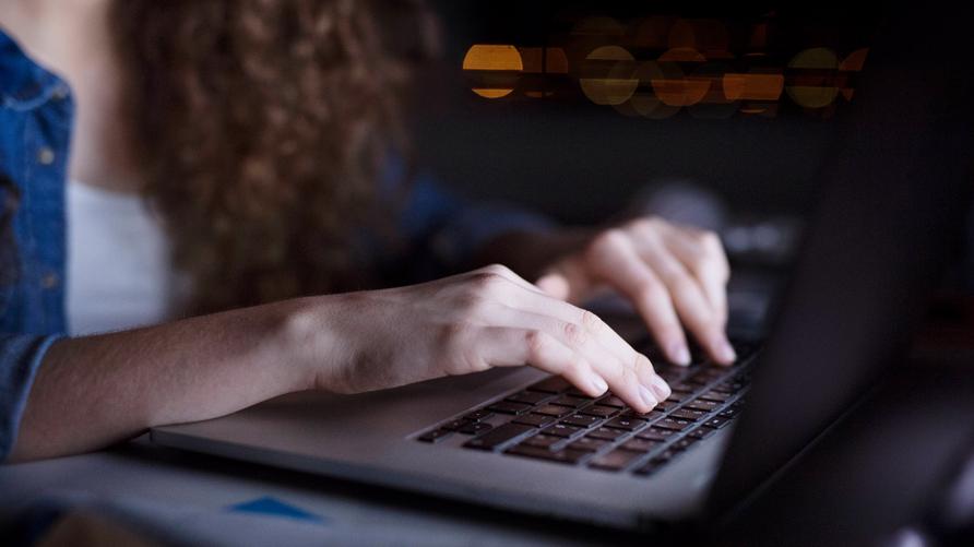 Wissenschaftliche Mitarbeiterin: Close up of university student is writing her thesis on a laptop at night, sitting at home at table, focusing on her research. Preparing for final exam, studying. Close up of hands of university student is writing her thesis on a laptop at night, sitting at home at table, focusing on her research. Preparing for final exam, studying. model released