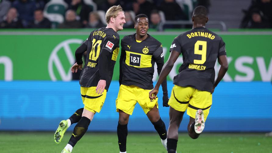 Bundesliga, 15. Spieltag – Sonntag: Dortmund's German midfielder #10 Julian Brandt (L) celebrates with Dortmund's English forward #43 Jamie Bynoe-Gittens (C) and Dortmund's Guinean forward #09 Serhou Guirassy  after scoring the 0-3 goal during the German first division Bundesliga football match between VfL Wolfsburg and Borussia Dortmund in Wolfsburg on December 22, 2024.