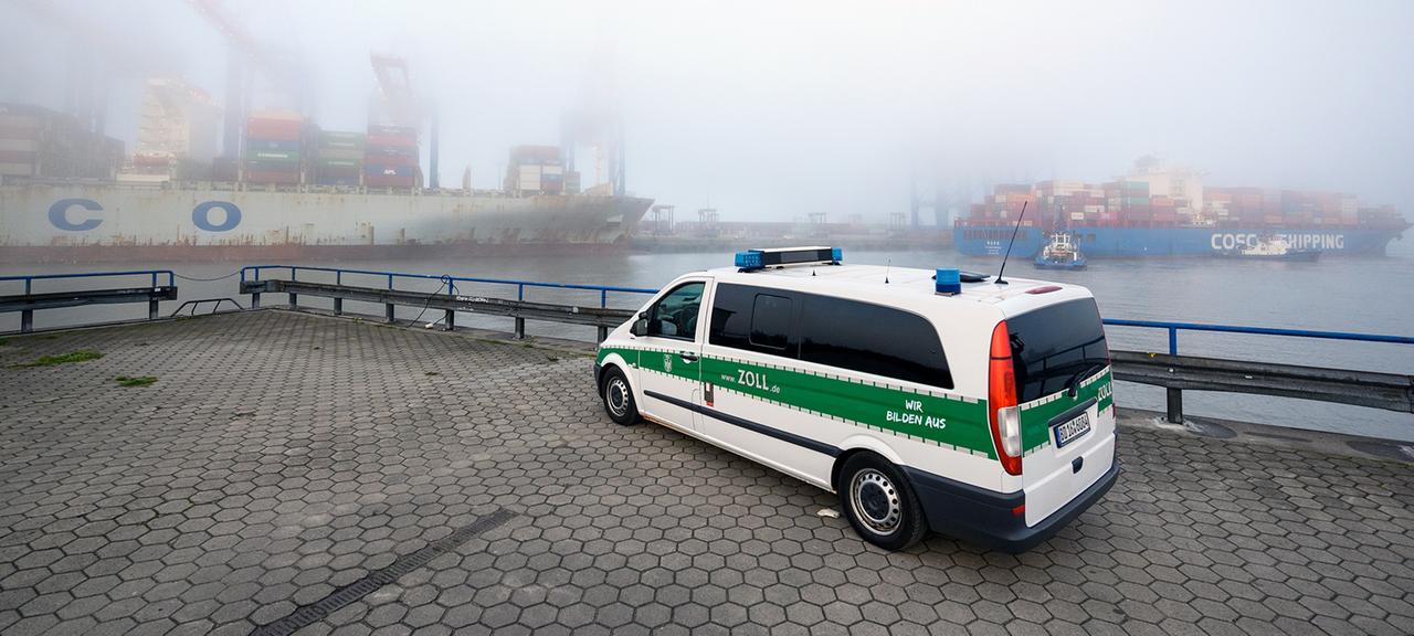 Ein Einsatzfahrzeug des Zolls steht gegenüber dem im Nebel liegenden Containerterminal Tollerort. 