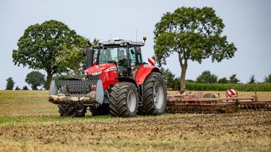 Ein Traktor fährt über ein abgeerntetes Feld .