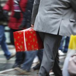 Mann im Anzug mit Geschenk in der Hand geht durch Menschenmenge, Bewegungsunschärfe vermittelt Hektik