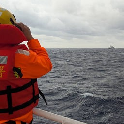 Ein Besatzungsmitglied an Bord eines Schiffes der taiwanischen Küstenwache beobachtet ein Schiff der chinesischen Küstenwache.