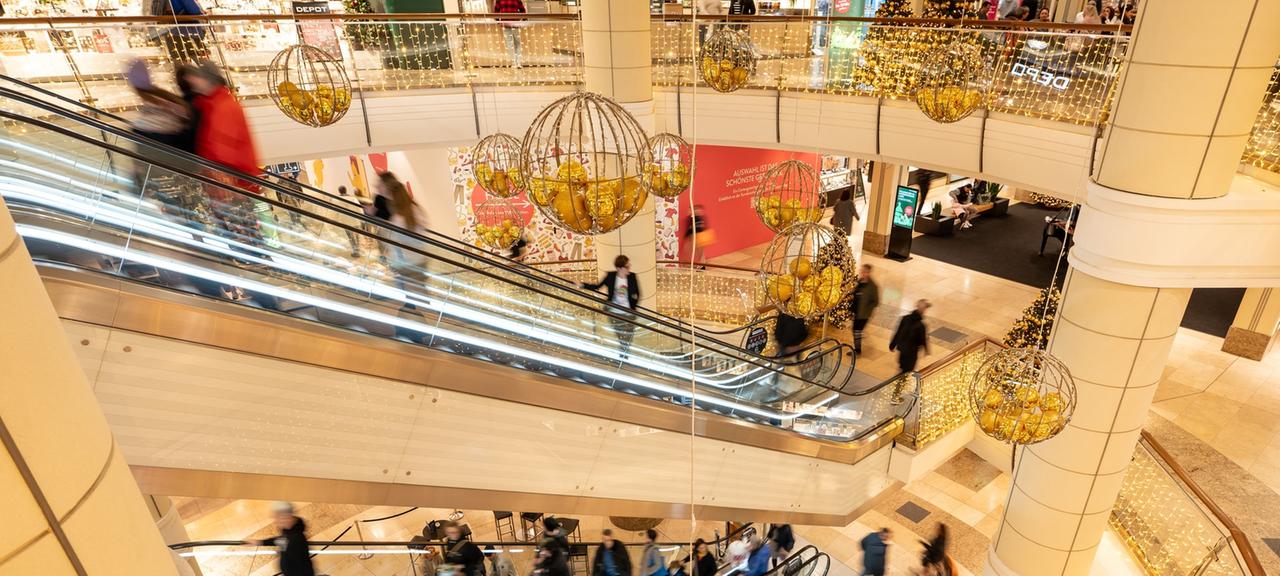 Menschen gehen in Sindelfingen durchs Breuningerland, das weihnachtlich dekoriert ist.