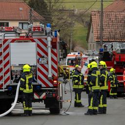 Löschfahrzeuge und Feuerwehrmänner stehen auf einer Dorfstraße mit Fachwerkhäusern.