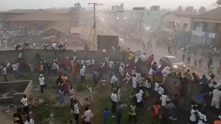 Menschen klettern in Nzerekore nach einer Massenpanik während eines Fußballspiels über eine Mauer