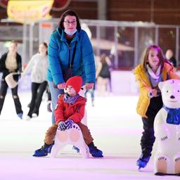 Frau mit Kindern auf der Eisbahn