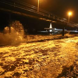 Wasser peitscht im Dunkeln gegen einen Brückenpfeiler.