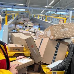 Zwei Frauen posieren vor einer Vielzahl von Paketen.