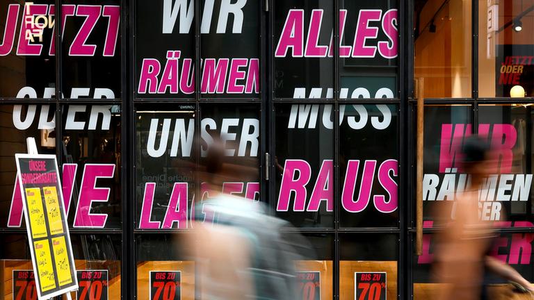 Schilder zum Räumungsverkauf hängen in einem Schaufenster.