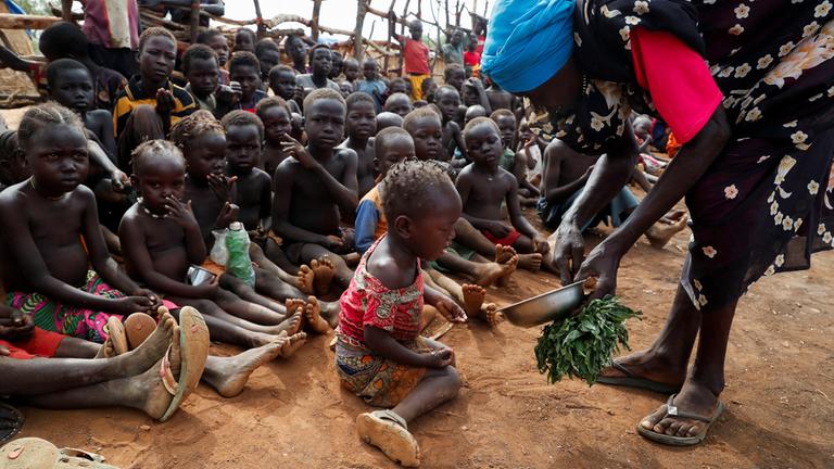 Kindern bekommen im Flüchtlingslager Bruam, Sudan wild gekochte Blätter als Nahrung.