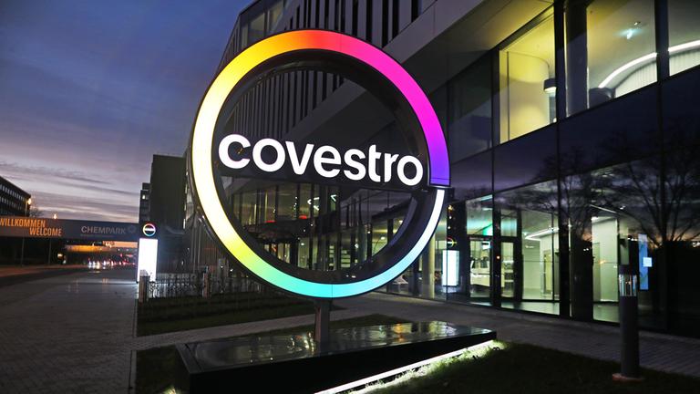 Das Logo des Kunststoffkonzern Covestro leuchtet vor der Unternehmenszentrale am Chempark Leverkusen.