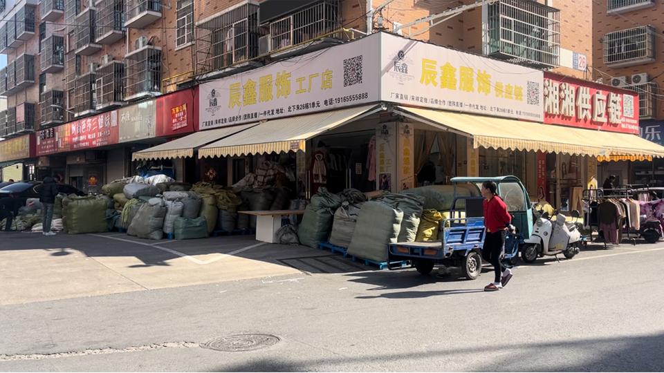 Säcke mit Waren stehen vor den Geschäften in einer Straße in Yiwu.