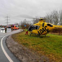 Ein Rettungshubschrauber steht auf einer Wiese neben einer Autobahnauffahrt.