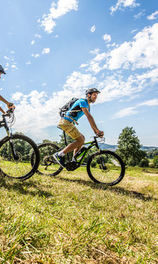 Pärchen fährt Mountainbike einen Hügel hinab