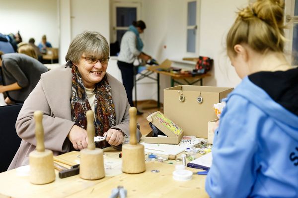 Themenbild Senioren Alt und Jung - Seniorin und junge Frau beim Basteln an einem Tisch