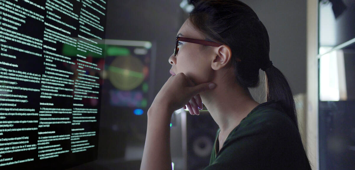 woman with hand near her face looking at a computer screen