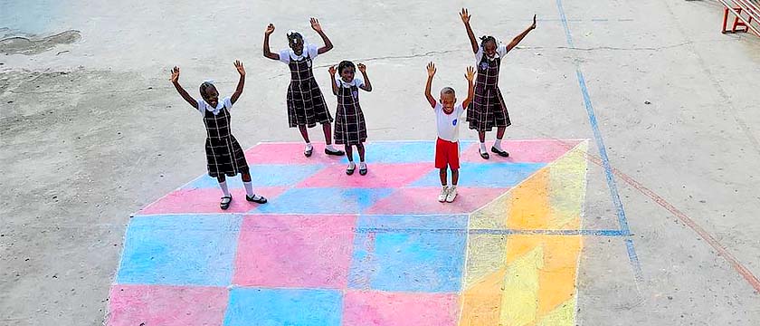 A Golden Spiral formed on the schoolyard floor by children sitting on a row, and continued toward the center with flowers in a variety of warm colors