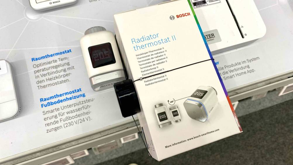 Heizkörperthermostat getestet: Ein Gerät auf einer Infotafel, daneben die Originalverpackung.