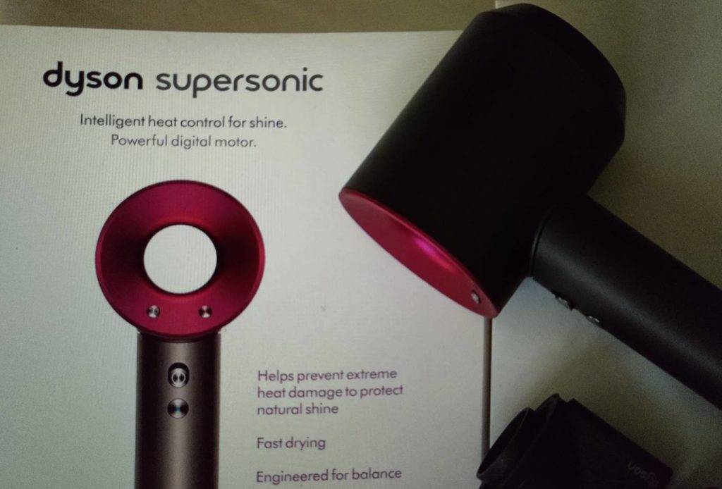 Haartrockner im Test: Seitliche Nahaufnahme eines Dyson Supersonic Modells im rosa-schwarzen Design auf seiner Originalverpackung.