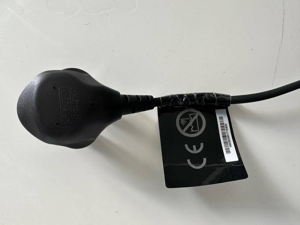 Ein Stromkabelstecker mit einem Label des getesteten ghd-Glätteisens von oben auf einer hellen Fläche.