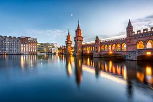 Singlereisen im Test: Die Lichter der Oberbaumbrücke in Berlin spiegeln sich auf dem Wasser.