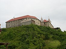 A large stone building with two towers on the top of a hill