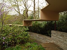 An image of the path from the main house to guest wing. Above the path is a concrete canopy with "steps", which appears as though it is floating.