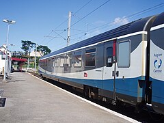 Vue d'un wagon bleu et blanc sur un quai de gare.