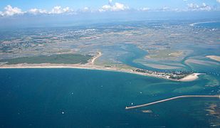 Vue aérienne d'une côte maritime avec une jetée en premier plan.